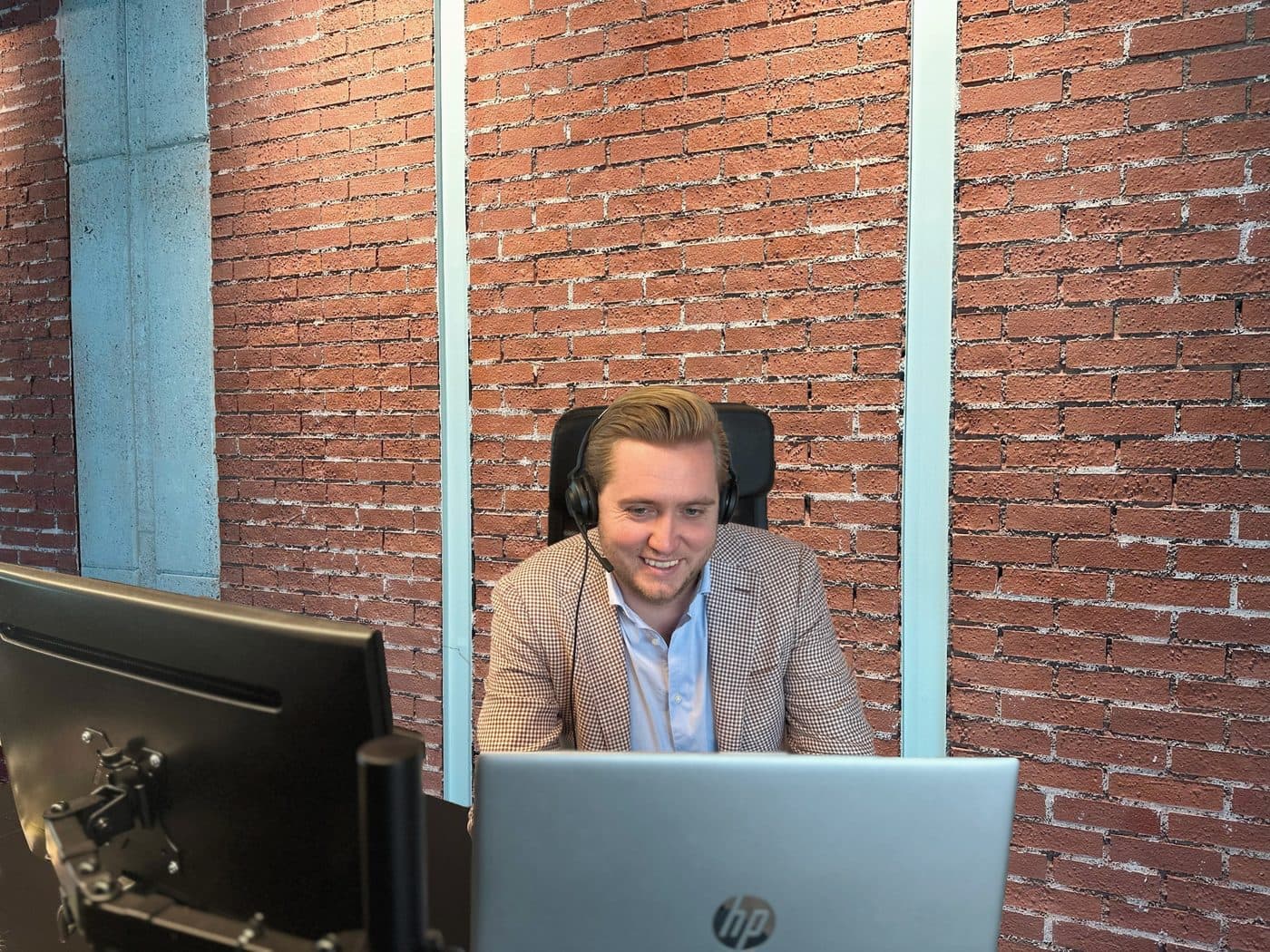 Un recruteur à son bureau contre le mur en briques, avec son casque
