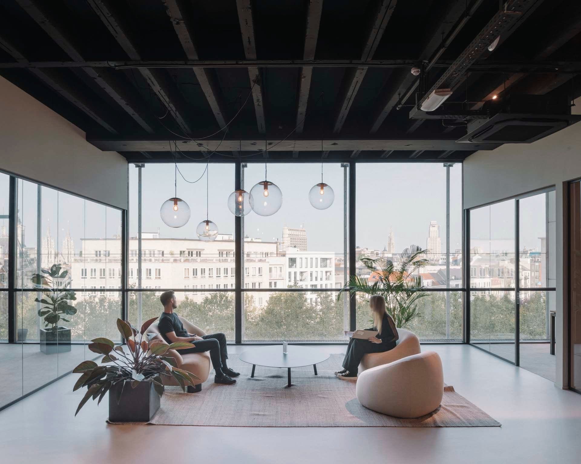 Deux collègues dans le lounge de notre bureau d’Anvers, avec vue sur la ville