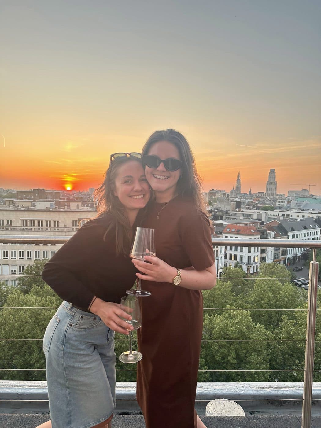 Twee collega's bij zonsondergang op het dakterras, met zicht op Antwerpen