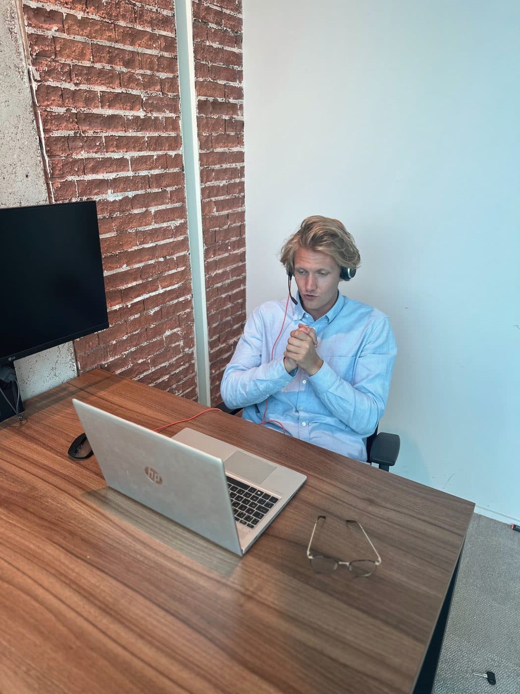 Een recruiter belt met zijn headset op, aan zijn bureau