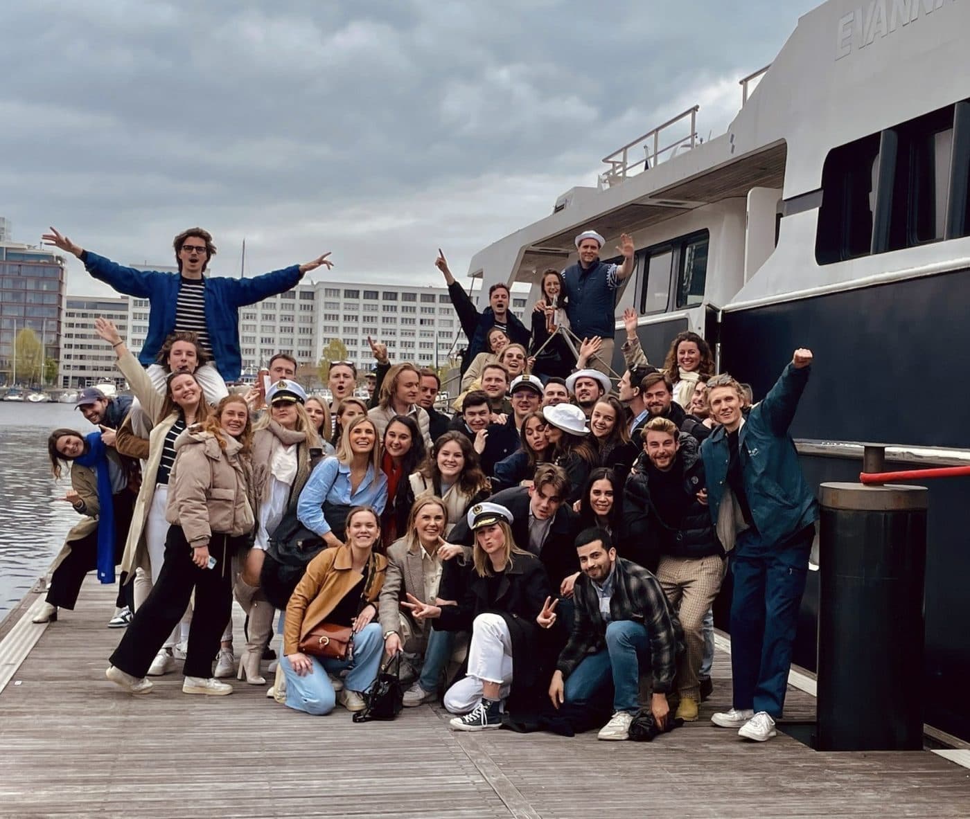 Het hele team samen op de kade bij een boot, de armen in de lucht