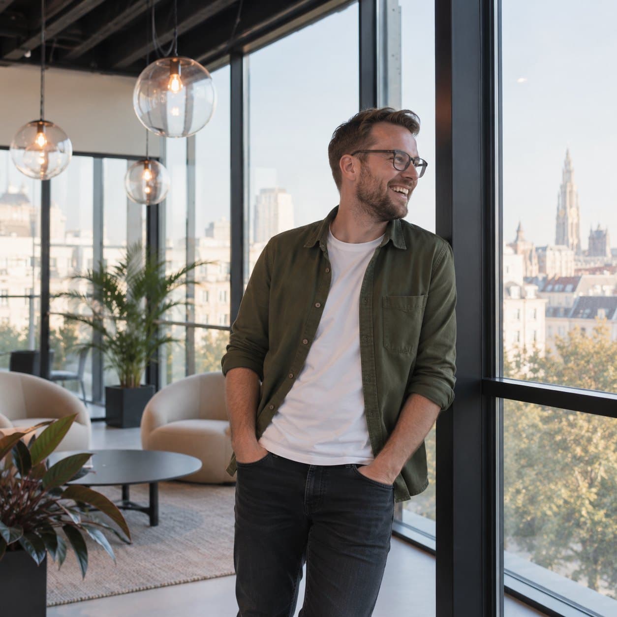 Een partner leunt lachend tegen het raam, met zicht op Antwerpen