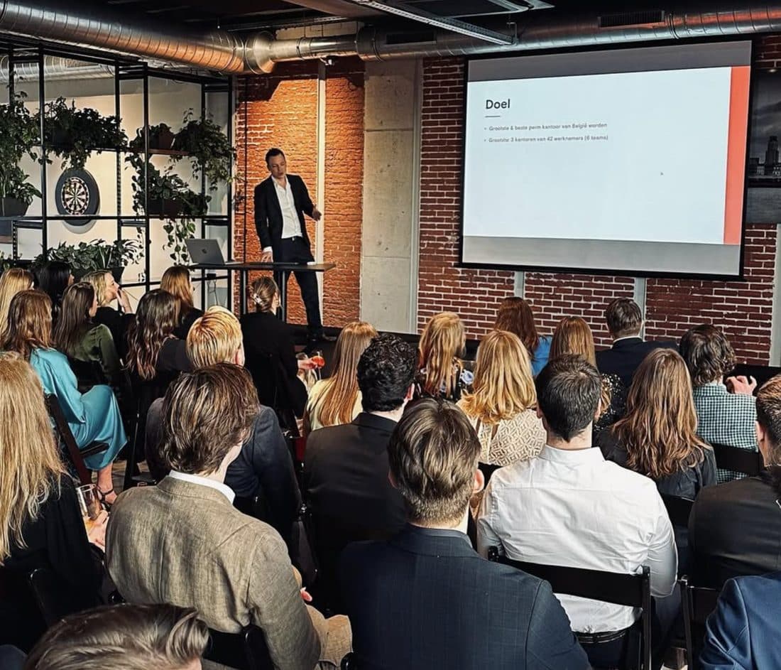 Een volle zaal collega's luistert naar een presentatie